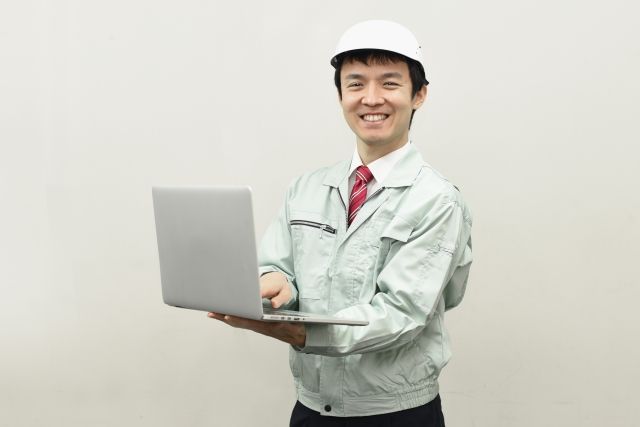 パソコンを持った作業服の男性